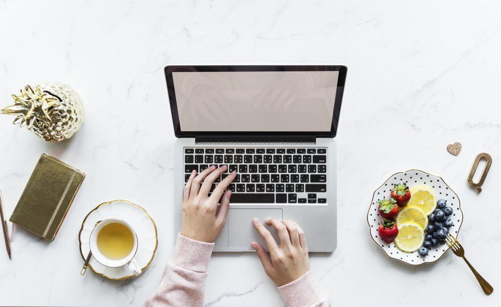 aerial view of woman using a computer laptop on a marble table scaled